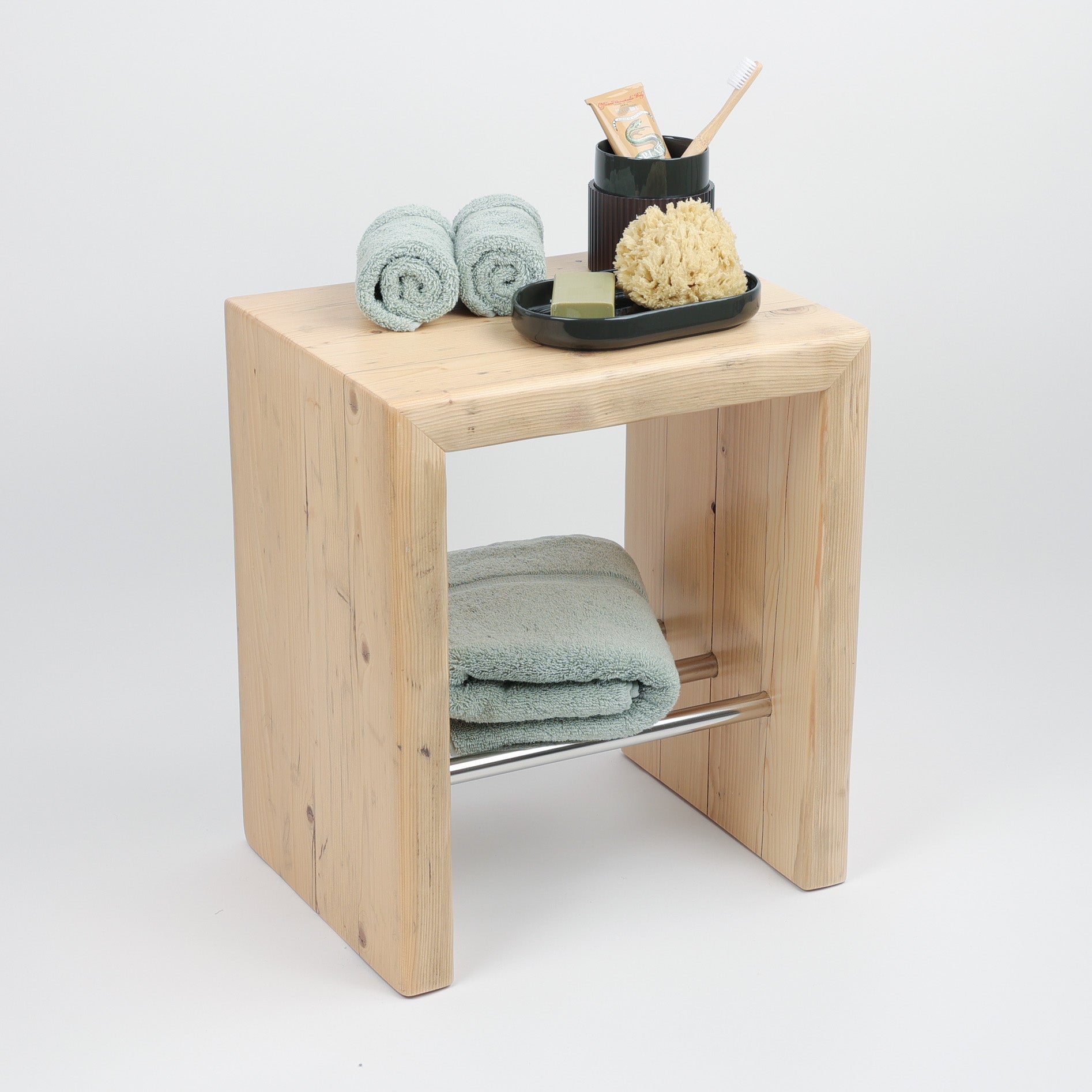 Der Hocker bietet eine praktische Ablagefläche, auf der Zahnputzbecher und Schalen Platz finden, beides Serie ofline von Decor Walther. Die Handtücher in jadegrün sind von Rhomtuft.