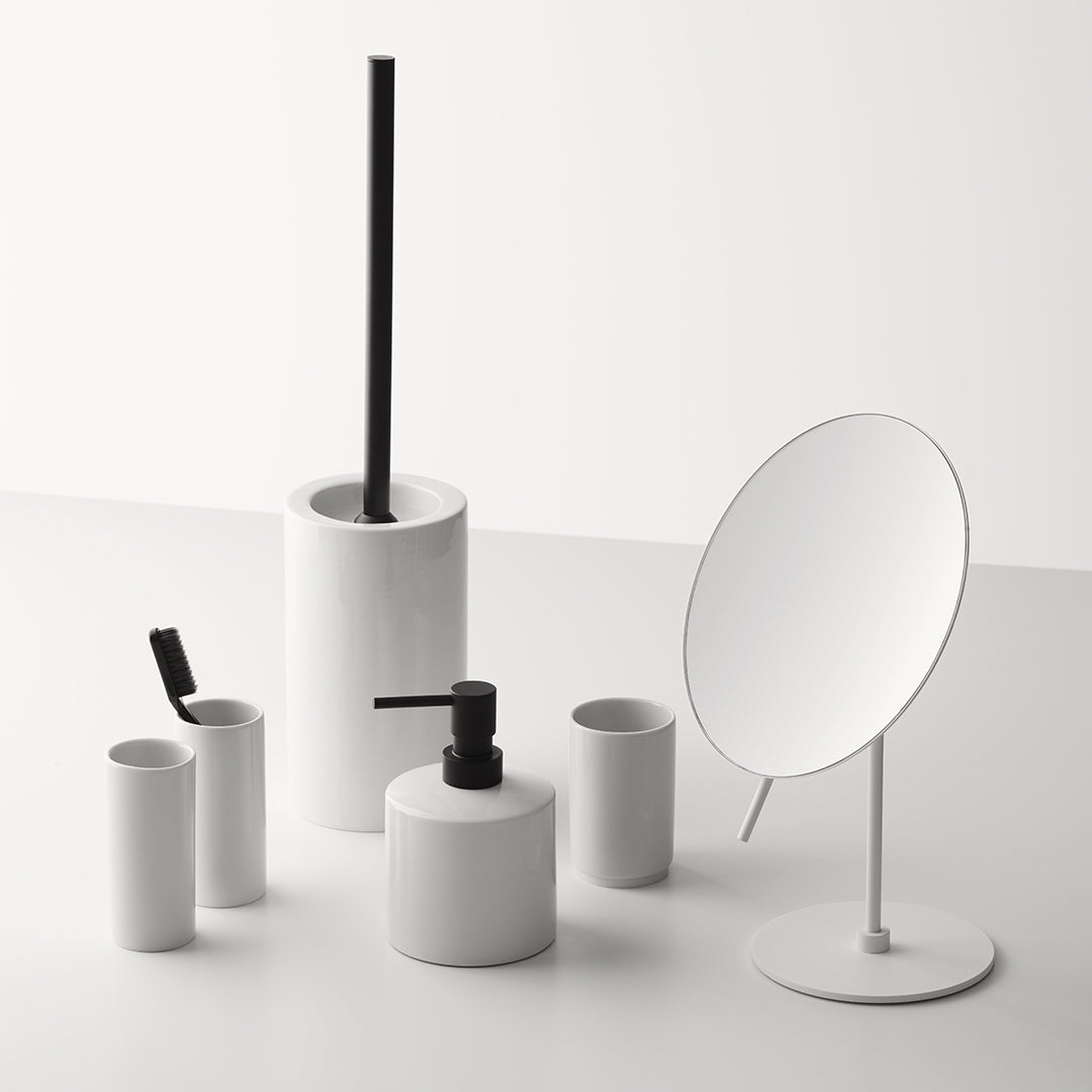 Weißes Porzellan-Badaccessoire-Set von Decor Walther mit schwarzer WC-Bürste, Seifenspender mit Schwarz-matt-Pumpe, Bechern und rundem Standspiegel in puristischem Design.