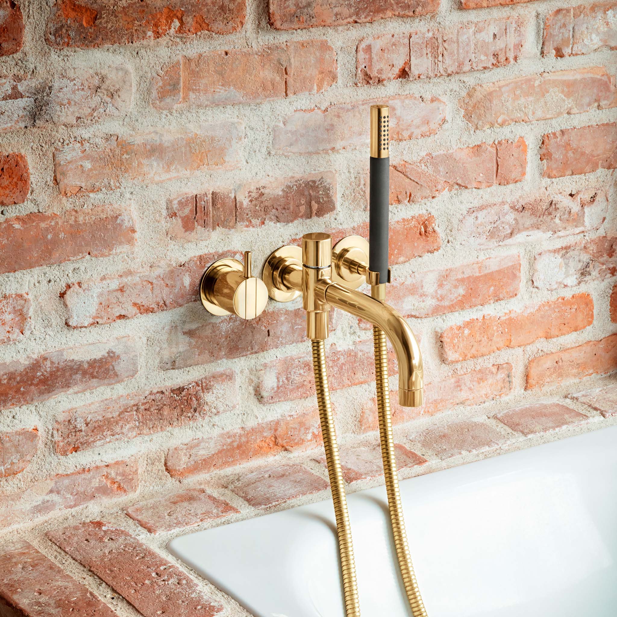 Vola Badewannenarmatur in Messing natur mit ruhigem Wasserauslauf und schlanker Handbrause – entwickelt eine edle Patina.