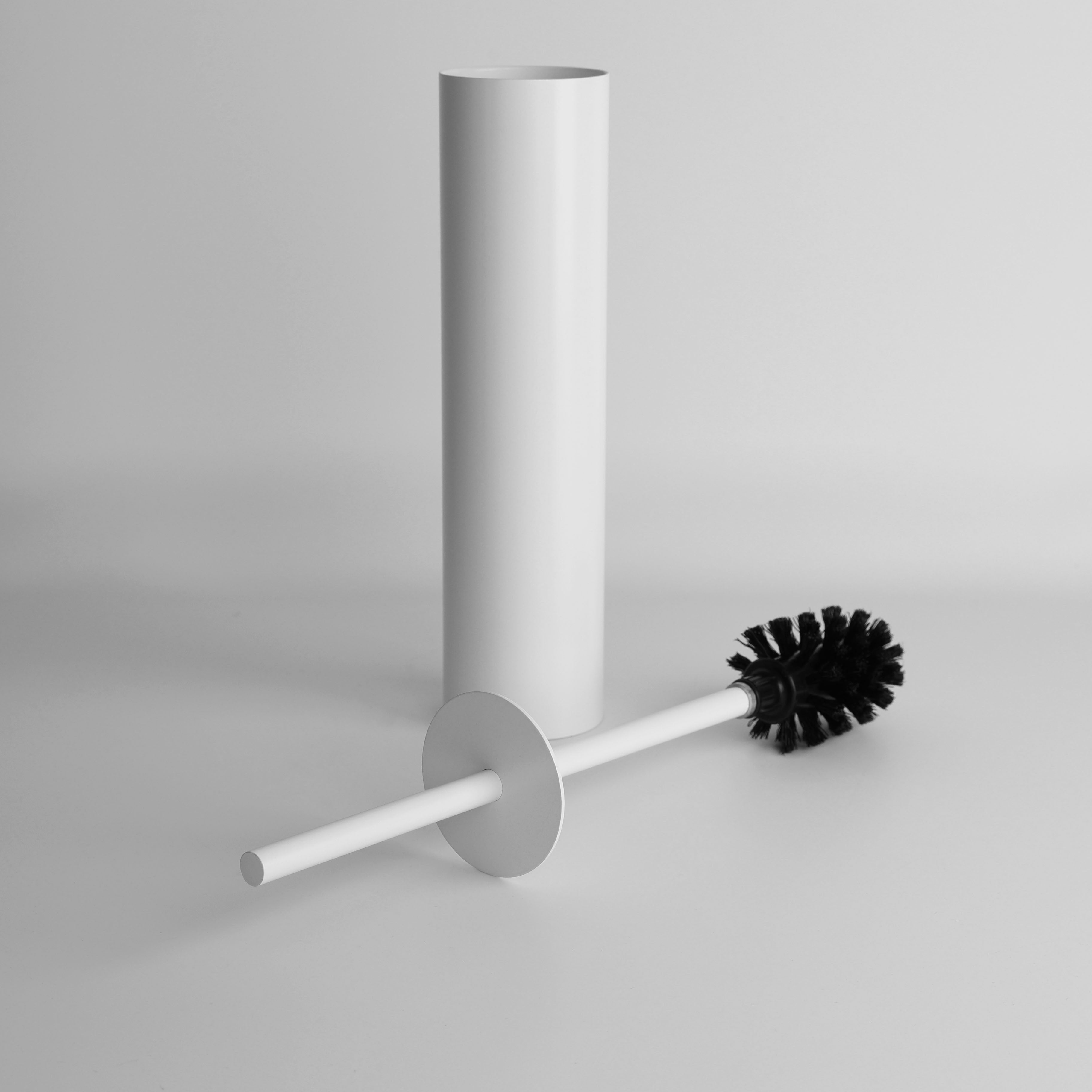 Ein weißer WC-Bürstenhalter mit entnommener Bürste, die daneben liegt. Der zylindrische Halter und die schwarzen Borsten der Bürste sind vor einem schlichten Hintergrund zu sehen.