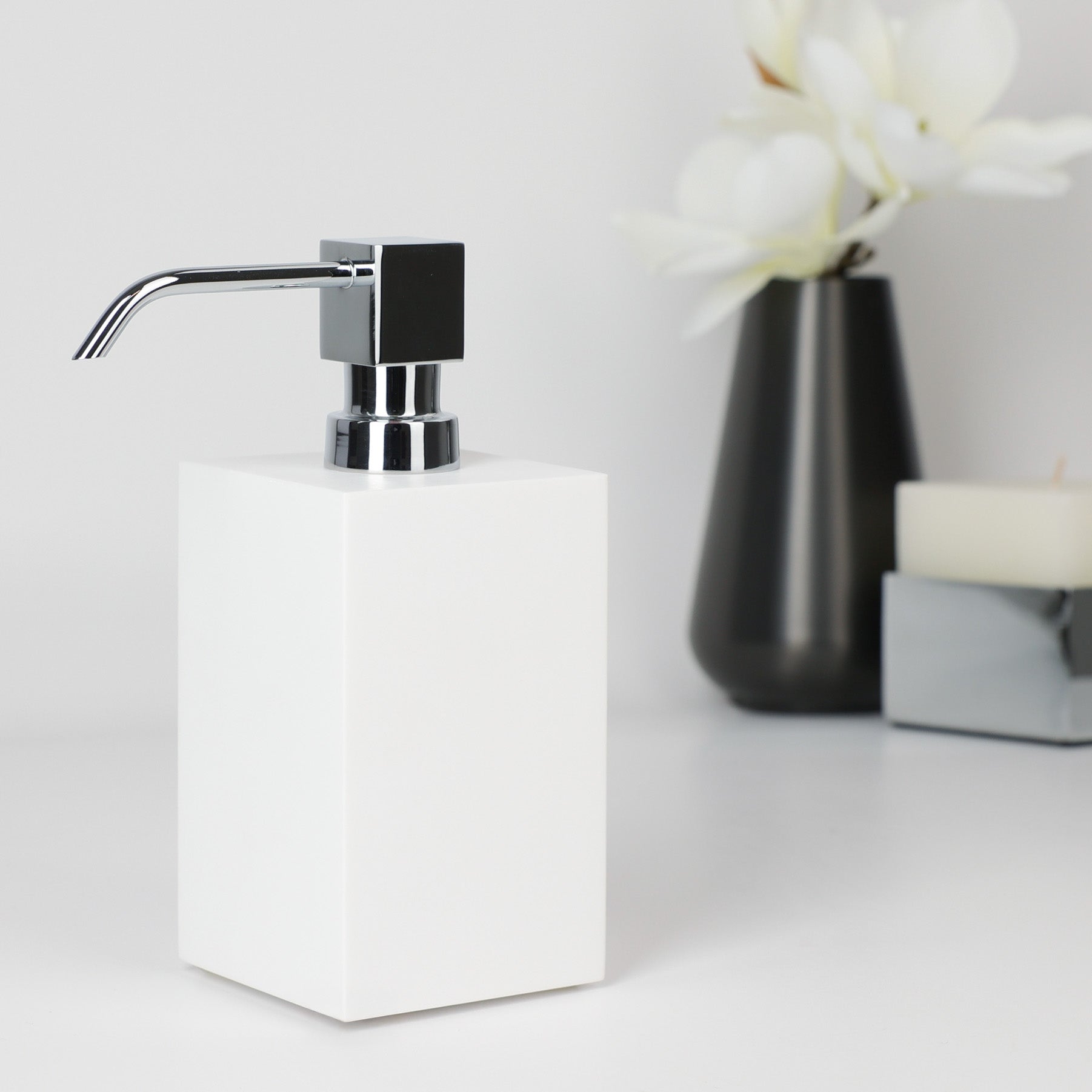 Corian Seifenspender hergestellt von dasfeinebad, 300 ml Fassungsvolumen, Design pur für jeden Tag, Blumenvase von Frost und Duftkerze von Decor Walther im Hintergrund