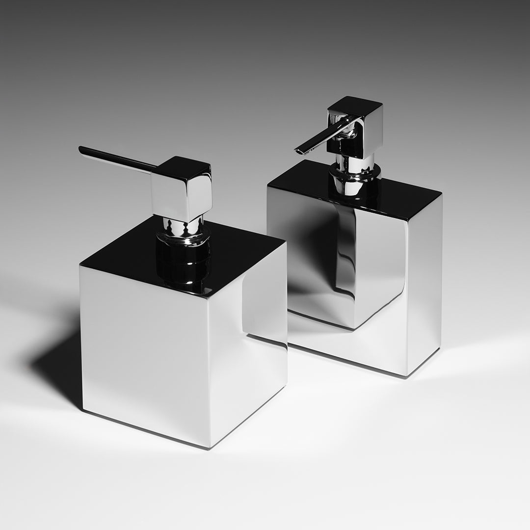 Zwei freistehende, eckige Seifenspender aus verchromtem massivem Messing von Decor Walther, nebeneinander stehend und glänzend reflektierend vor neutralem Hintergrund.