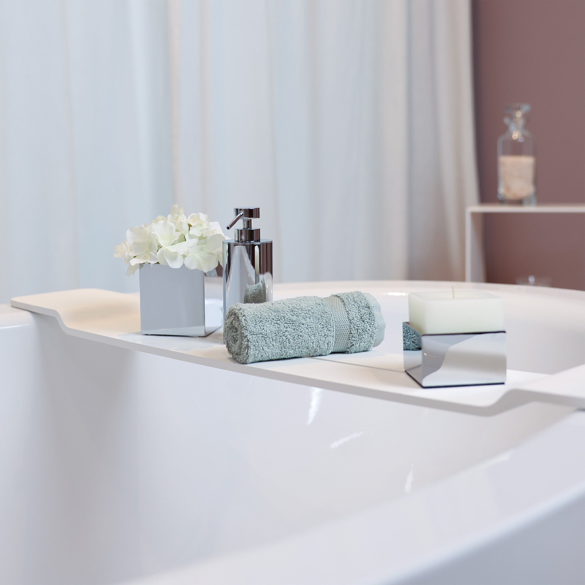 Glänzendes Arrangement auf der Badewanne von Decor Walther - Ablage Stone in matt weiss - Kerzenhalter und Utensilienbehälter aus der Brick Serie - Handtuch in jadegrün von Rhomtuft - Seifenspender  von Windisch