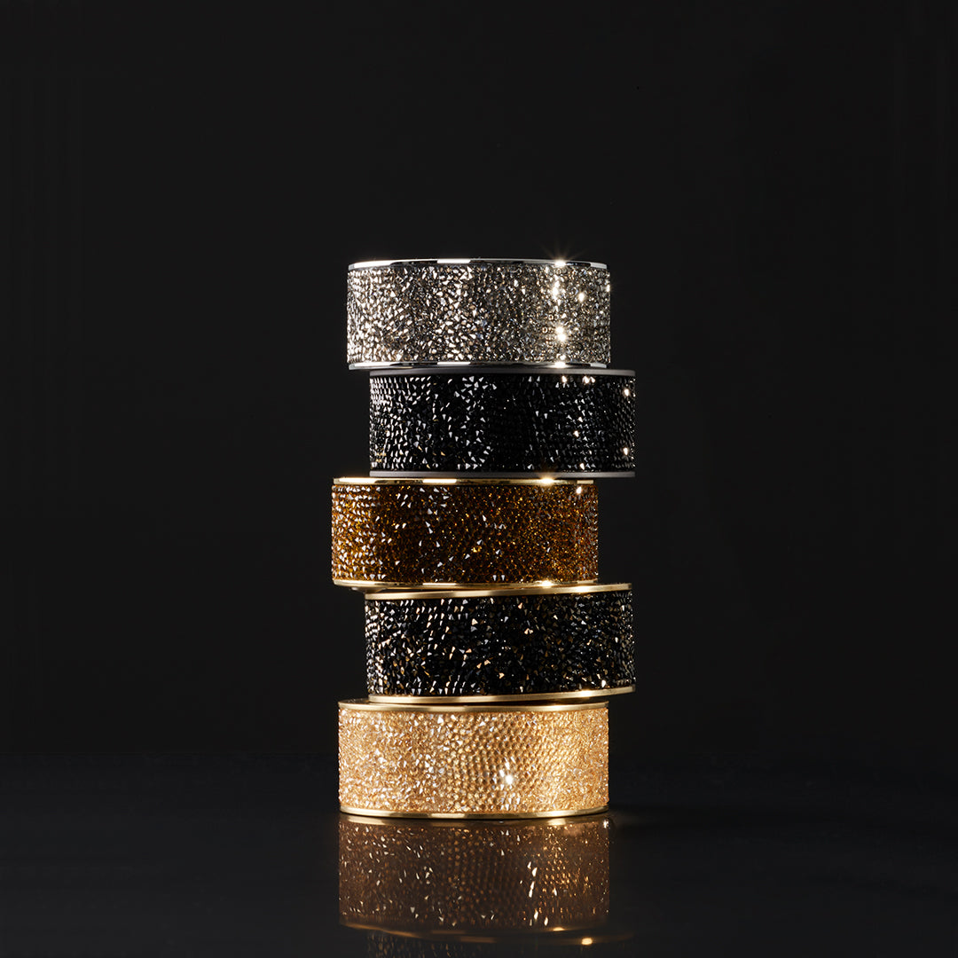Gestapelte Swarovski-Kristallbänder der Decor Walther Rocks Kollektion in Chrom, Schwarz, Gold und Gold matt – funkelnde Nahaufnahme der verschiedenen Kristallvarianten.