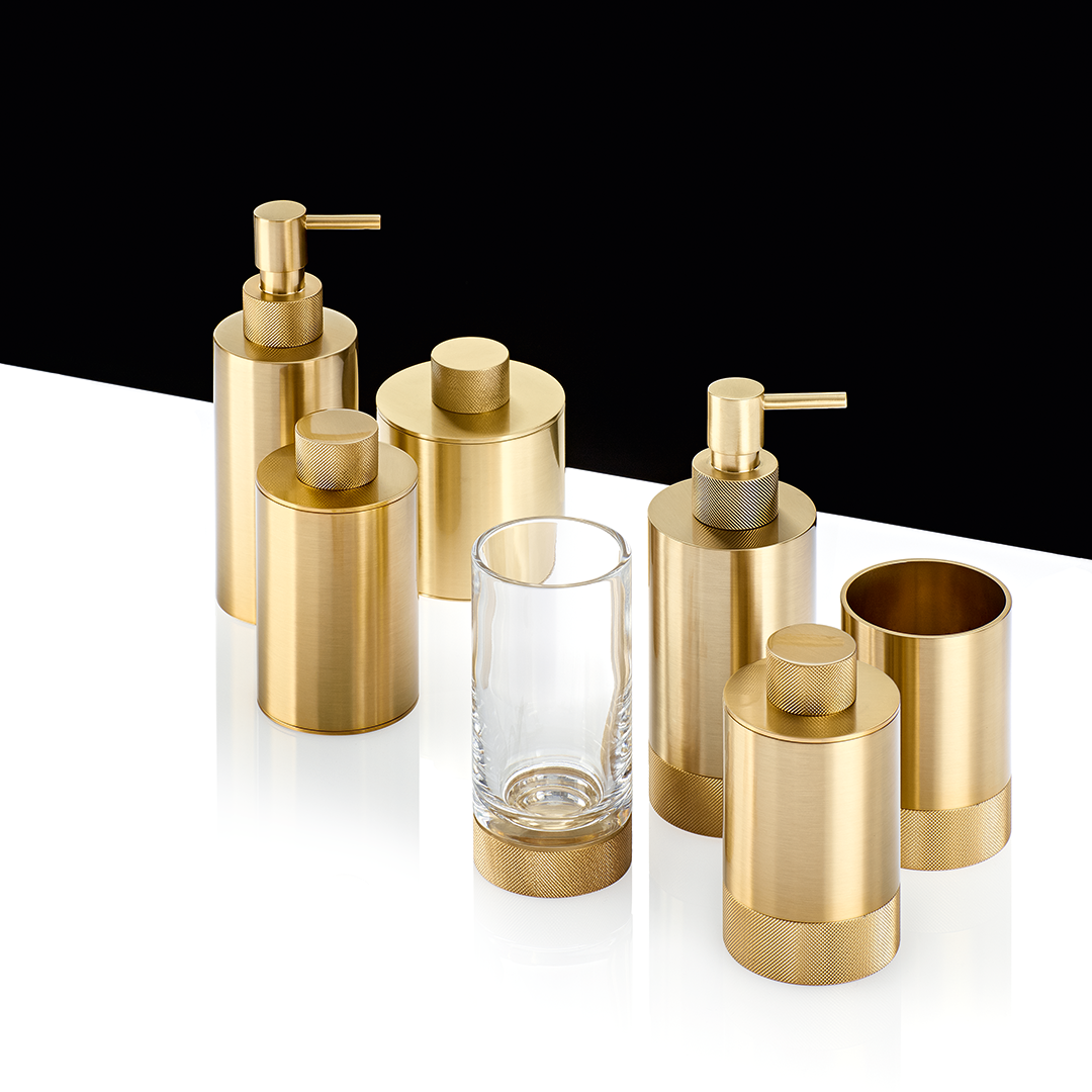 Elegantes Set aus der Club Kollektion für das Badezimmer, featuring Zahnputzbecher in mattem Gold (24 Karat) und klarem Kristallglas, begleitet von passenden, hochwertigen Badutensilien.