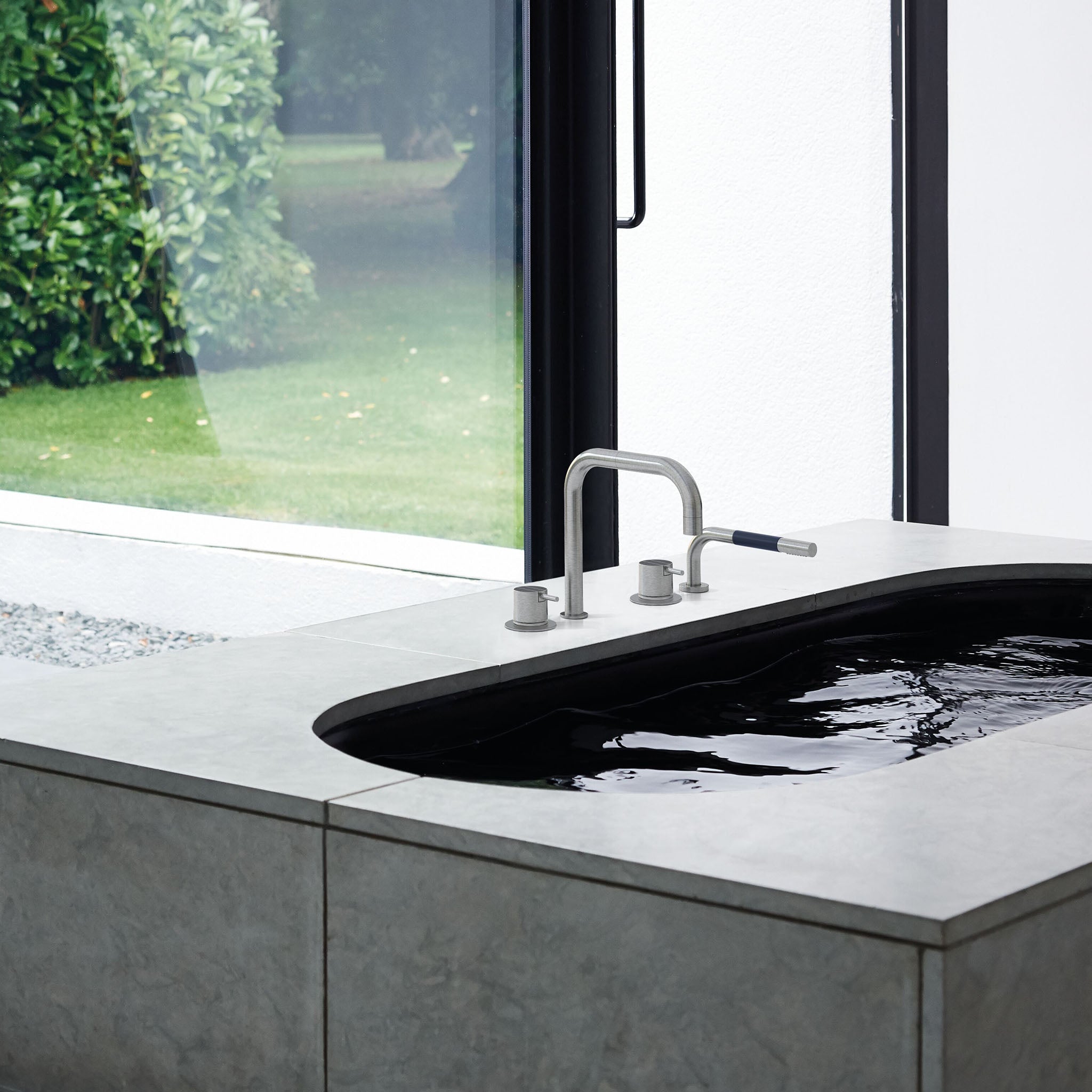 Vola SC10 in gebürstetem Edelstahl – moderne Wannenrandarmatur mit Auslauf und integrierter Handbrause.